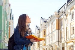 Travel. Young woman traveler with a backpack on her shoulder. Independent travel and out sightseeing in a history city. Student woman, her vacation. Learning foreign languages in a different country