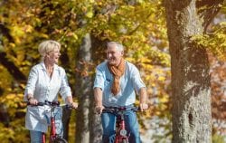 Senior couple, man and woman, on bicycles having bike tour in autumn park